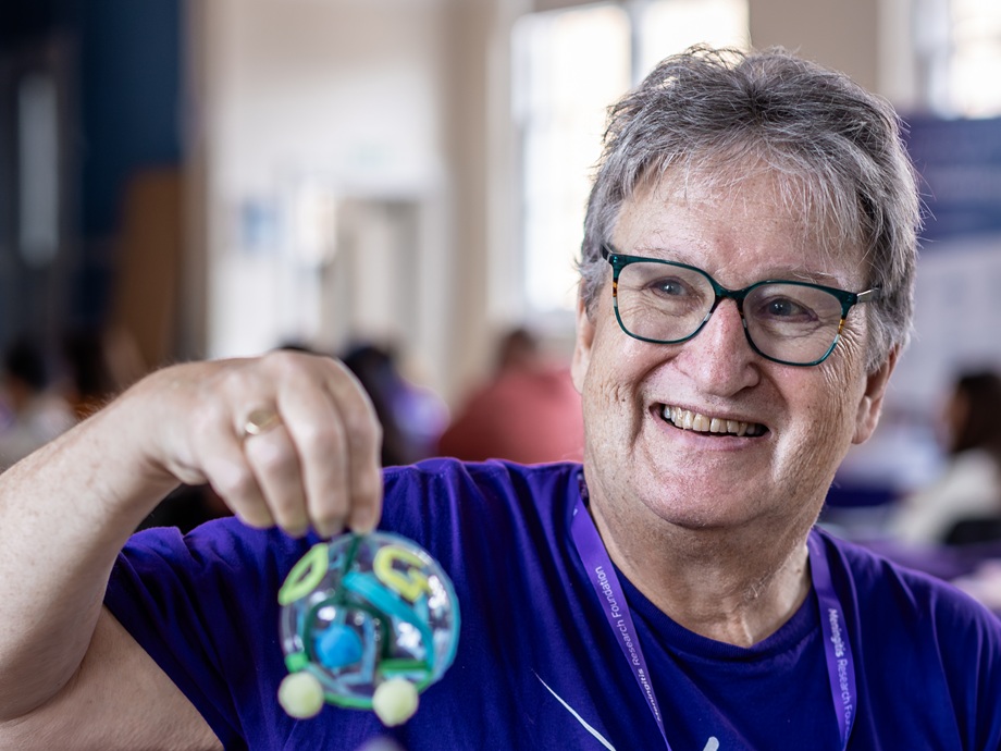 A Meningitis Research Foundation Ambassador holding a bauble and smiling.